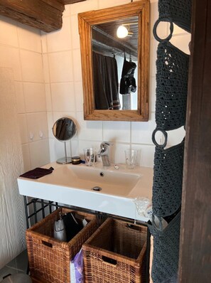 A bathroom with a wooden-framed mirror, a white sink, and wicker baskets under the counter. - Chalet in Kollnburg Near St. Englmar Ski Area (Kollnburg)