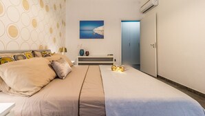 A bedroom with a bed, a nightstand, a painting, and a door.
