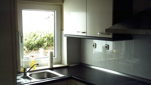 Une cuisine avec une fenêtre, des armoires blanches et un plan de travail noir.
