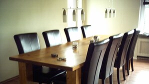Une table à manger avec des chaises, un plancher en bois et des luminaires suspendus.