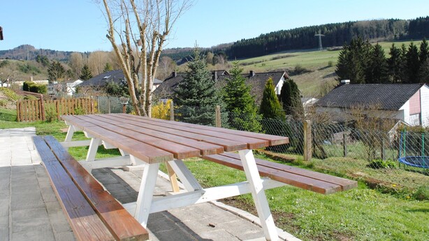 Une table de pique-nique dans un parc, avec en arrière-plan des maisons et des arbres.