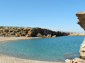A coastal landscape with rocky cliffs and clear blue waters.