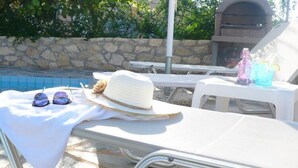 A poolside area with lounge chairs, a hat, and sunglasses on a towel. - Stylish Villa in Loutra with Private Pool & Garden near Sea Beach (Rethymno)