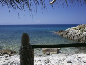 A rocky beach with clear water and a distant boat. - Mansion in Capo Vaticano Near the Beach (Ricadi)