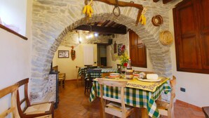 A rustic dining area with stone walls, wooden beams, and a checkered tablecloth. - Farmhouse in Marche With Pool and Views (Mercatello sul Metauro)