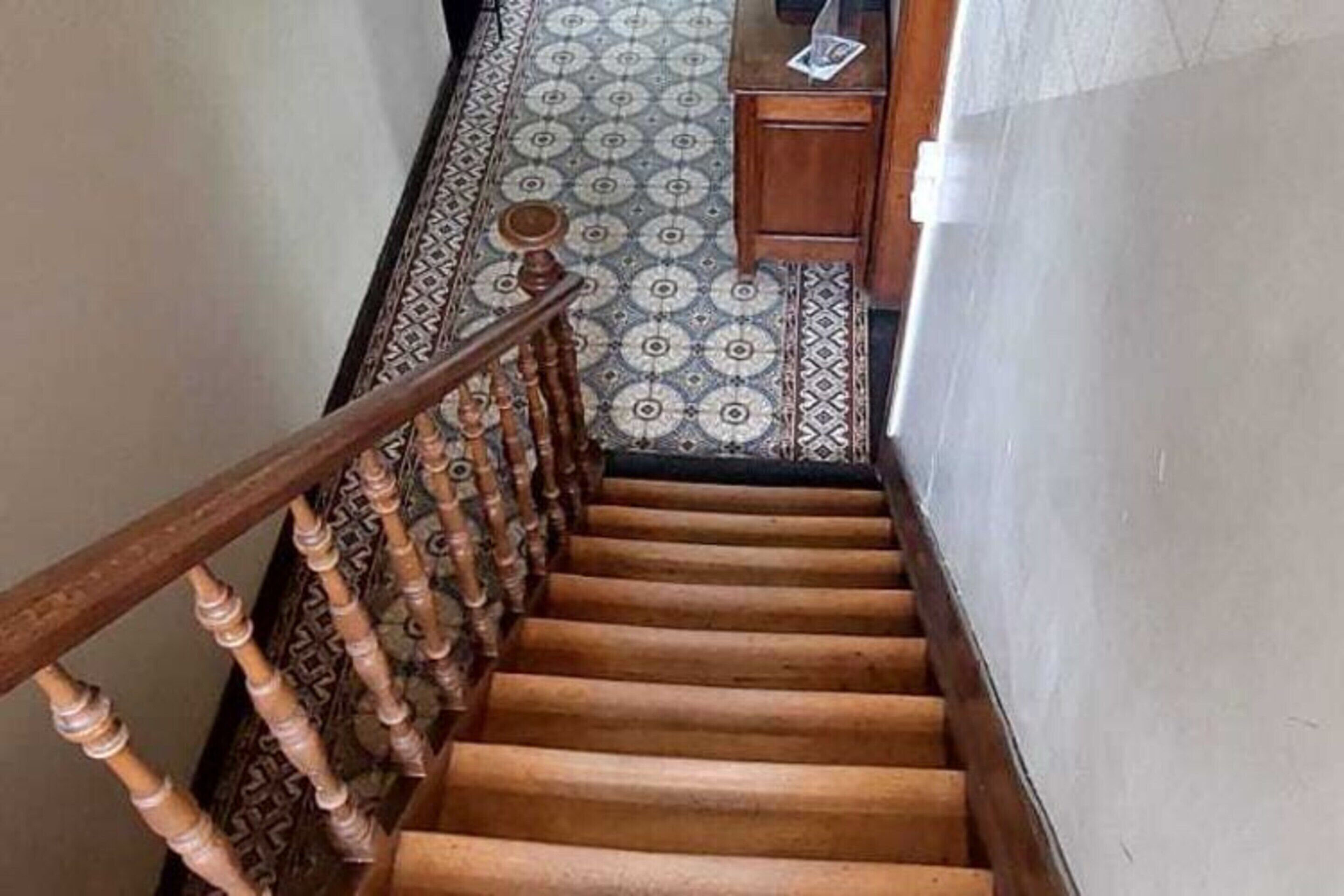 A wooden staircase with a patterned carpet.