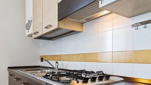 Une cuisine moderne dotée d’une cuisinière en acier inoxydable, de meubles en bois et d’un dosseret carrelé.