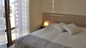 A hotel room with a bed, a nightstand, a lamp, and a window with curtains. - Holiday Home in Lazise Near Gardaland (Lazise)