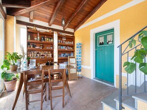 A cozy interior with wooden bookshelves, a dining table, chairs, and a staircase with a teal door. - Family Countryside Retrete (Stilo)