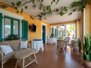 A cozy room with wicker furniture, a flat-screen TV, and a view of the outside. - Family Countryside Retrete (Stilo)