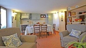A cozy living room with two sofas, a dining table, and a kitchen in the background. - Holiday Home in Tuscany With Pool & Vineyards (Cortona)