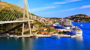 A cable-stayed bridge over a body of water with a cruise ship docked nearby. - Luxury Apartment With Private Balcony in Quiet Area (Dubrovnik)