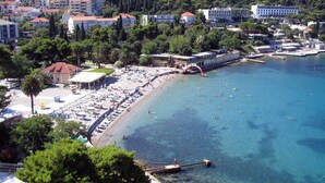 A coastal area with a beach, a pier, and buildings in the background. - Luxury Apartment With Private Balcony in Quiet Area (Dubrovnik)