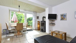 Una sala de estar con sofá, televisión y un comedor con sillas y mesa.