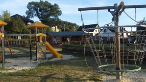Un parque infantil con tobogán, estructuras para escalar y una red de cuerdas.