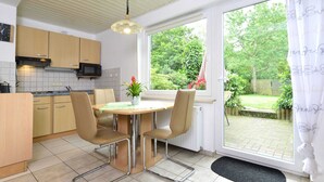 Una cocina moderna con comedor, una ventana con vistas a zonas verdes y una puerta que da al exterior.