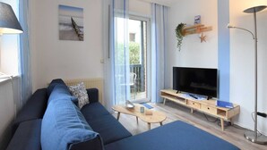 Un soggiorno moderno con un divano, una TV e un tavolino.