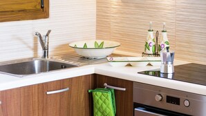 A modern kitchen with a stainless steel sink, a white bowl, a green oven mitt, and a built-in oven. - New Small Apartmentcomplex in Village of Prinès near Rethymnon (Rethymno)