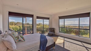 Une chambre avec un grand lit, une chaise et une vue sur les vignes, grâce à de grandes fenêtres.