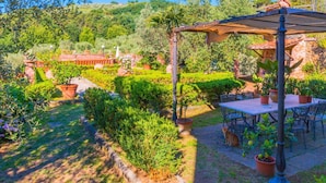 A garden patio with a pergola, outdoor seating, and a view of a lush landscape. - Nice Farmhouse in Montecatini Terme with Sauna & Hot Tub (Pieve a Nievole)