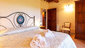 A bedroom with a bed, a nightstand, a chair, and a wooden wardrobe. - Belvilla by OYO Mimosa (Cortona)
