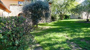 A courtyard with a stone building, a tall tree, and a well-maintained lawn. - Belvilla by OYO Mimosa (Cortona)