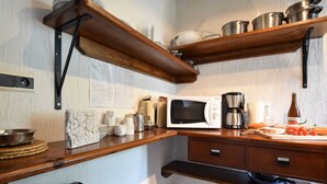 A kitchen with wooden shelves, a microwave, a coffee maker, and various kitchen utensils. - Tranquil Holiday Home in Houffalize With Barbecue (Houffalize)