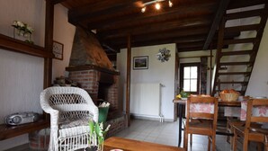 A cozy living room with a brick fireplace, wicker furniture, and a wooden table with potted plants. - Tranquil Holiday Home in Houffalize With Barbecue (Houffalize)