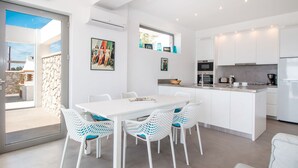 A modern kitchen with white cabinetry, a central island, and a dining area with white chairs. - Sea View Villa in Kalythies with Private Pool near 3 Beaches (Rhodes)
