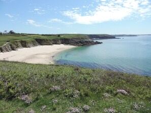 A coastal landscape with a sandy beach, grassy cliffs, and a clear blue sea. - Seaside house, 400 m from the beach, with fiber optics. (Plouarzel)