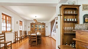 A spacious dining area with wooden furniture, a large cabinet with glassware, and a staircase leading to another level. - Belvilla by OYO Quaint Villa in Carini With Garden (Carini)