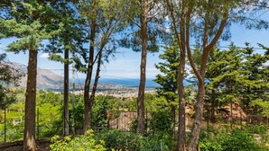 A garden with tall trees and a view of a cityscape in the background. - Belvilla by OYO Quaint Villa in Carini With Garden (Carini)