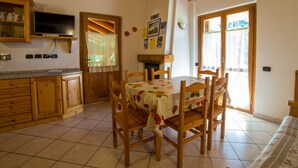 A cozy kitchen with wooden cabinets, a dining table with chairs, and a large window. - Belvilla by OYO Grbe Trilo Max (Antey-Saint-Andre)