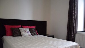 A neatly made bed with a white bedspread and multiple pillows, including red and patterned ones. - Grand Family Farmhouse in Anthisnes (Anthisnes)