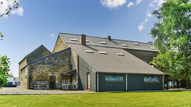 A modern building with a sloped roof, a stone exterior, and a large grassy lawn. - Grand Family Farmhouse in Anthisnes (Anthisnes)