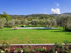 A pool area with lounge chairs and a well-maintained lawn, surrounded by trees and hills in the background. - Holiday Home in Castiglion Fiorentino w/ Pool (Castiglion Fiorentino)