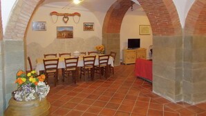 Un coin repas agrémenté d’une arche en briques, d’une table dressée pour six personnes et d’un téléviseur posé sur un meuble.