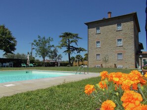 Ein Steinhaus mit Schwimmbad und Außenbereich zum Sitzen.