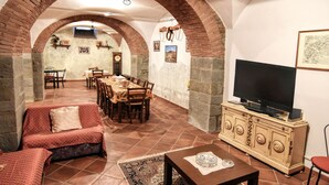 Un coin repas agrémenté d’une arche en briques, d’un téléviseur et d’un canapé.