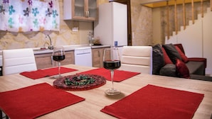 A dining area with a wooden table set for two, two glasses of red wine, and a decorative centerpiece. - Luxurious Villa in Bali Crete With Private Pool (Mylopotamos)