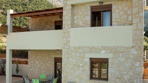 A two-story stone building with a patio area featuring outdoor furniture and a pool. - Luxurious Villa in Bali Crete With Private Pool (Mylopotamos)