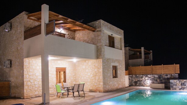 A two-story stone building with a swimming pool, outdoor seating, and a covered patio area. - Luxurious Villa in Bali Crete With Private Pool (Mylopotamos)