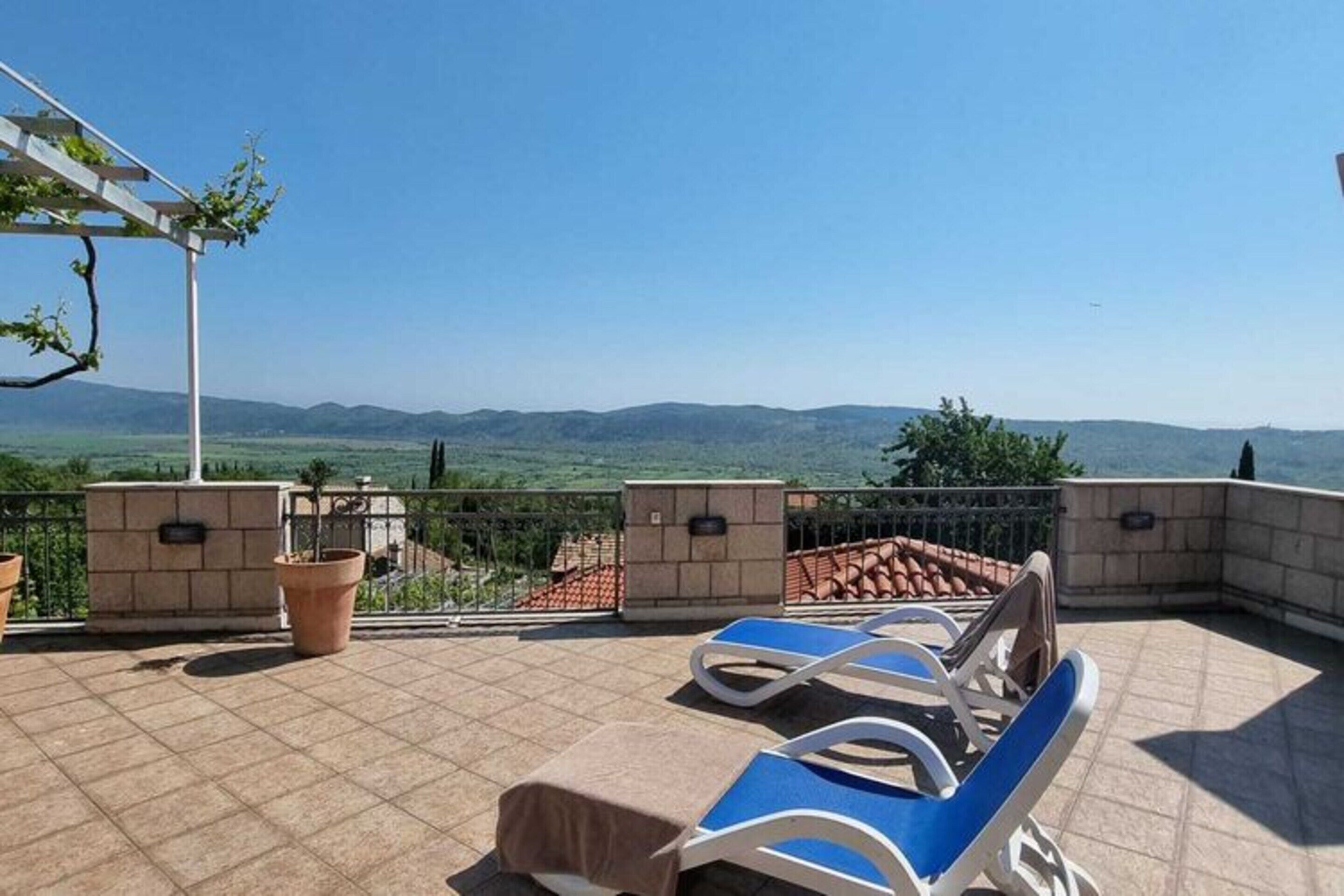 Una terrassa amb seients relaxants, plantes en testos i vista a les muntanyes llunyanes.