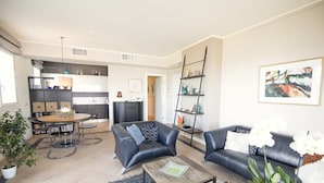 A modern living room with a sofa, coffee table, and a dining area with a table and chairs. - Apartment With Terrace for 4 People (Olbia)