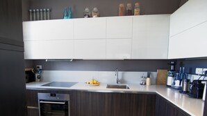 A modern kitchen with dark wood cabinets, a stainless steel sink, and a built-in oven. - Apartment With Terrace for 4 People (Olbia)