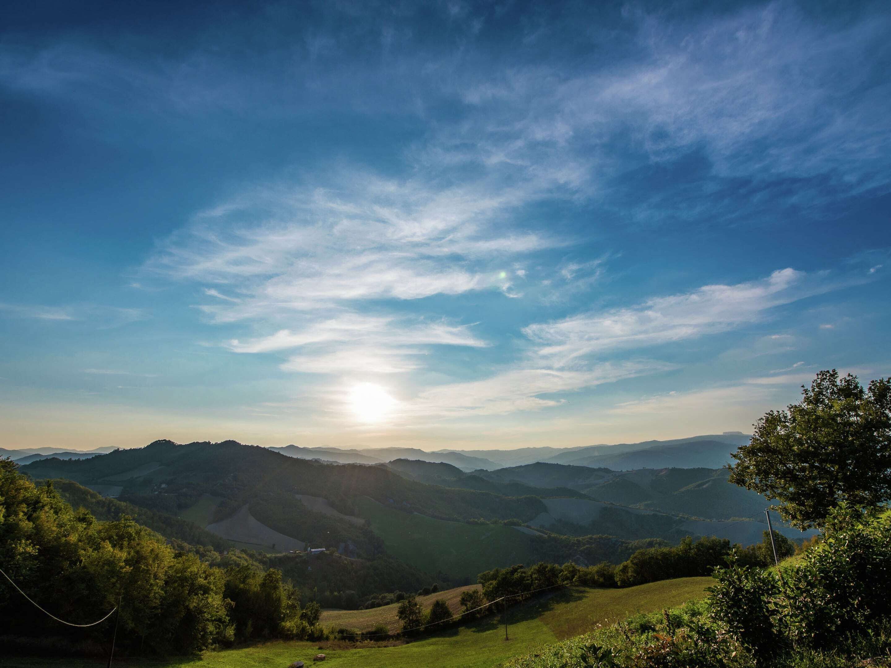 Panoramica su dolci colline e un cielo sereno con il sole splendente.