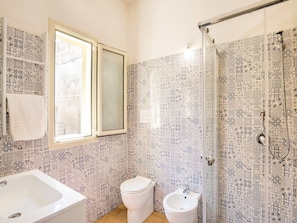 A bathroom with patterned tiles, a white sink, a toilet, and a bidet.