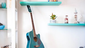 A teal guitar on a stand in a room with teal shelves, a vase, and a small plant. - Simplistic Villa in Scoglitti near Sea Beach (Vittoria)