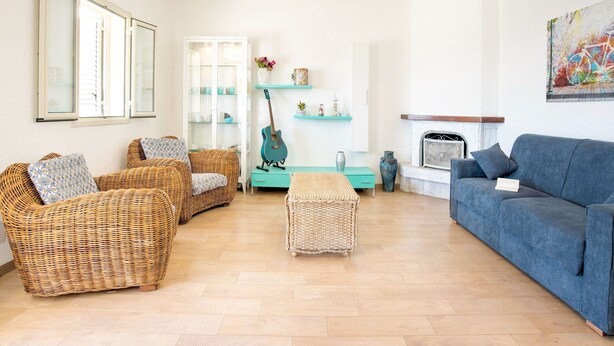 A living room with wicker furniture, a teal side table, a blue sofa, and a fireplace. - Simplistic Villa in Scoglitti near Sea Beach (Vittoria)