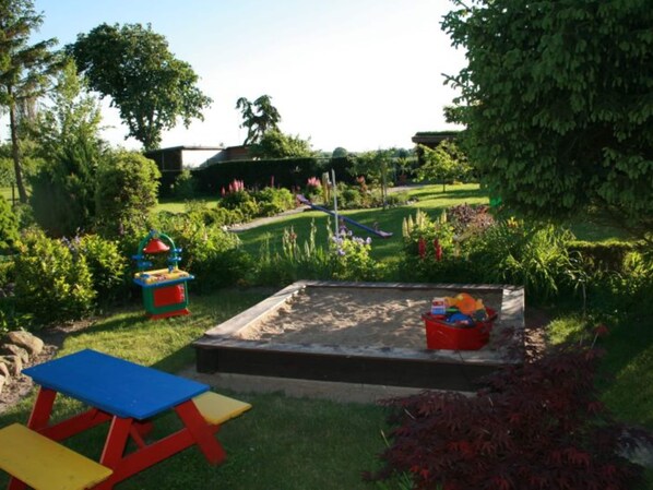 A garden with a sandbox, a slide, and a picnic table. - Kinderparadies - Ferienwohnung mit Garten (Blowatz)